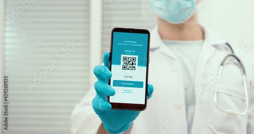 Portrait of a doctor man holding a smartphone with a negative test results for coronavirus. Digital health passport. The concept of a new normal and travel during the pandemic.