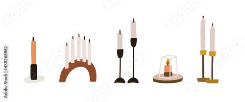 Set of modern wax candles with metal and wooden candlesticks, holders, and pe...