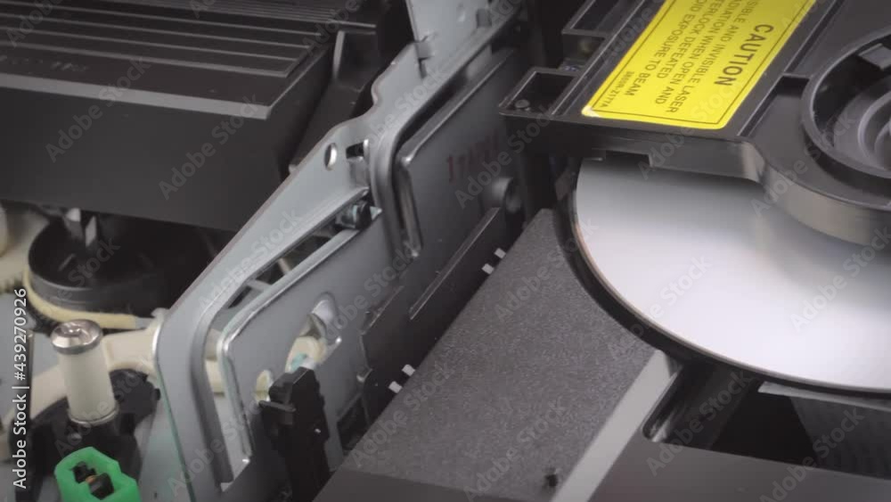 Closeup shot showing a dvd and a vhs cassette being inserted into a player. Camera slowly moving sideways.