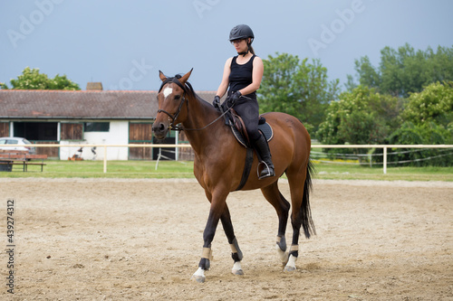 The girl in black with helmet rides a sorrel horse