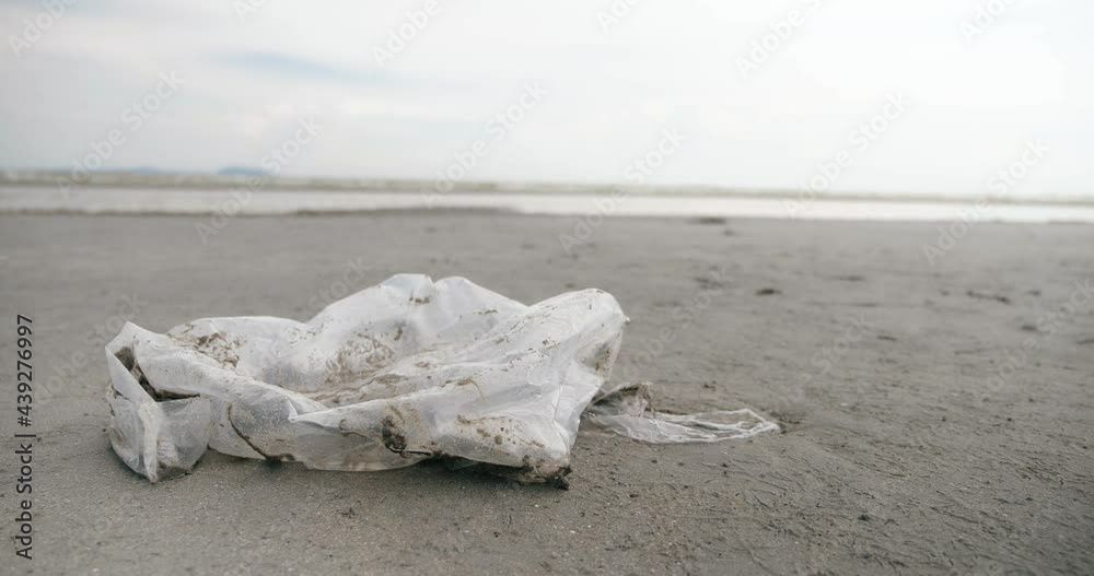 Close up a plastic carrier bag pollution on sea beach. Ecological concept, Beach pollution. Garbage on a beach. Close up a plastic carrier bag pollution on sea beach. Ecological concept, Beach pollution. Garbage on a beach.