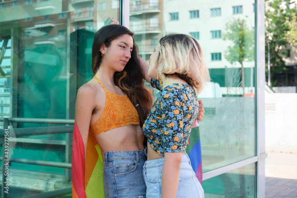 Lesbian couple hugging and looking to each other at street.