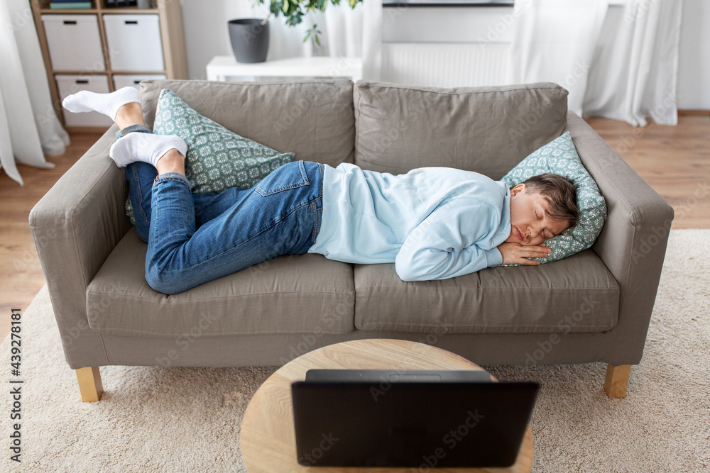 people, boredom and depression concept - lazy young man sleeping on sofa at home