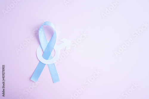Prostate cancer awareness blue ribbon with white paper male sign mars arrow copy space on pink background. Men healthcare concept, men carcinoma symbol.