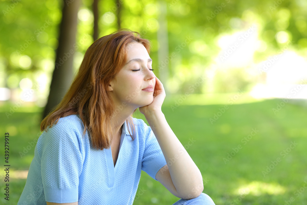 Relaxed woman sitting in a park with closed eyes Relaxed woman sitting in a park with closed eyes