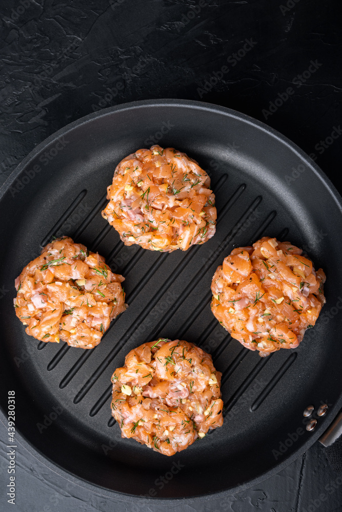 Raw fish patties with salmon and lemongrass, on black textured background, flat lay