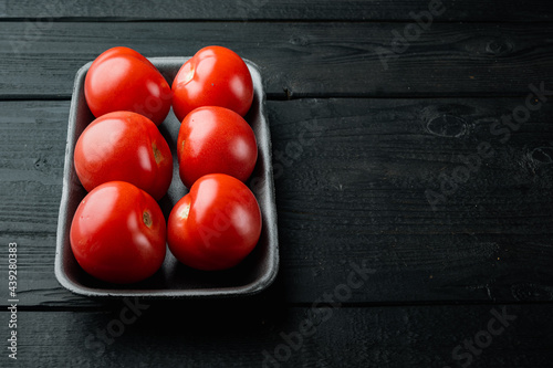 Red tomatoe, on black wooden table with copy space for text