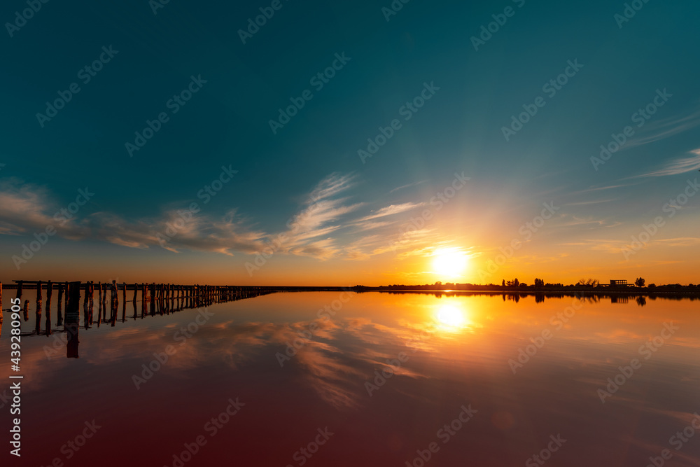 Obraz premium pink lake and sandy beach with a sea bay under a blue sky with clouds