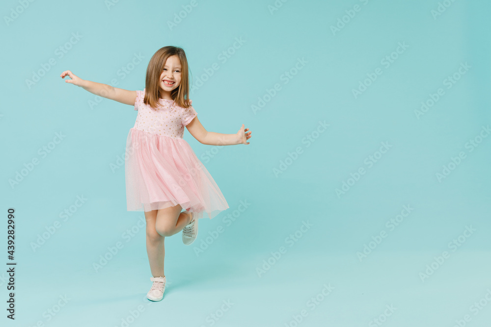 Full size body length little fun cute kid girl 5-6 years old wears pink dress dancing isolated on pastel blue color background child studio portrait. Mother's Day love family people lifestyle concept. Full size body length little fun cute kid girl 5-6 years old wears pink dress dancing isolated on pastel blue color background child studio portrait. Mother's Day love family people lifestyle concept.