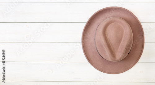 Fotografie A fedora hat made of beige or powdery colour felt, on the wall of white boards