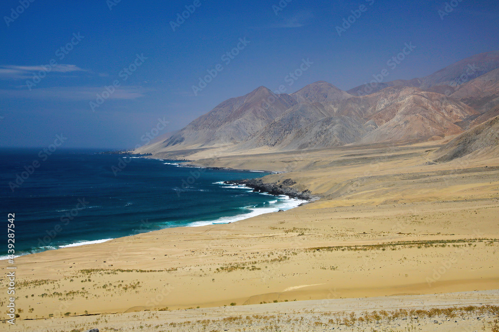 Rough harsh coastal scenery: View on uninhabited barren bay with empty sand beach at endless pacific coast with dry arid mountains - Pan de Azucar, Chile Rough harsh coastal scenery: View on uninhabited barren bay with empty sand beach at endless pacific coast with dry arid mountains - Pan de Azucar, Chile