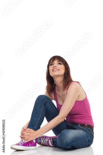 Cheerful Young Woman Is Sitting On A Floor Looking Up