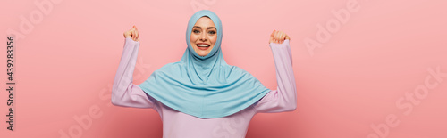 Photography cheerful muslim woman showing yeah gesture on pink background, banner