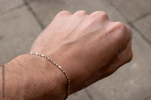 Male hand palm with hairs, visible vein scar and silver bracelet with blurred background photo