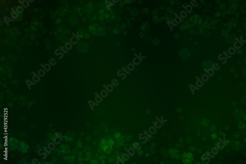 Dark green bokeh background on four leaf clover pattern background.