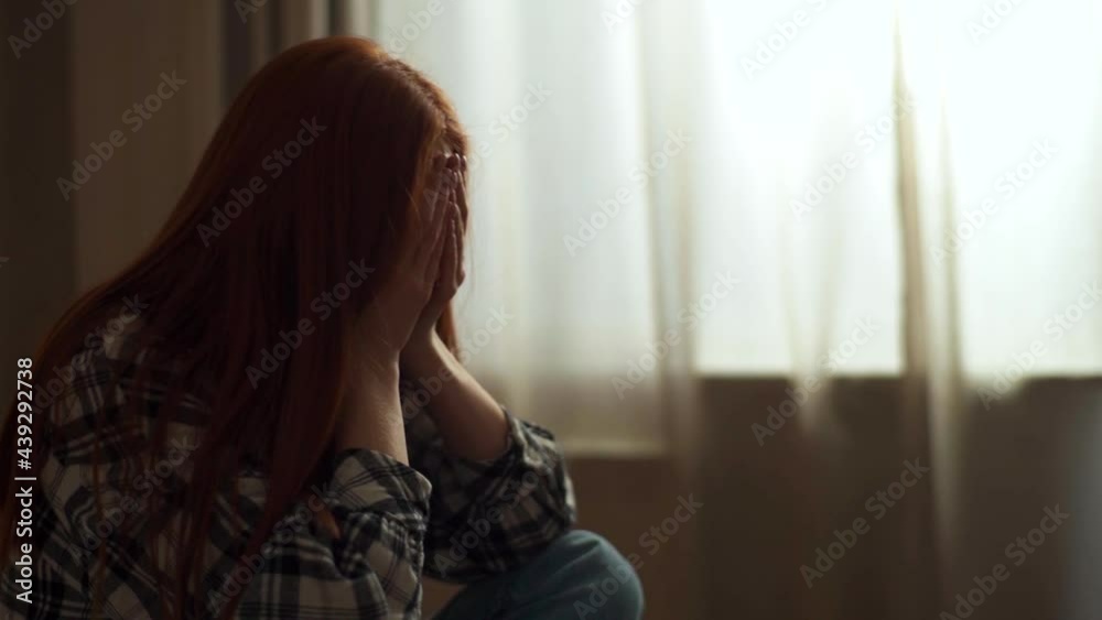 Close-up of unrecognizable desperate young woman suffering from depression sitting on bed in dark bedroom. Stressed sad female crying swaying alone covering face and eyes. Shooting in slow motion. Close-up of unrecognizable desperate young woman suffering from depression sitting on bed in dark bedroom. Stressed sad female crying swaying alone covering face and eyes. Shooting in slow motion.