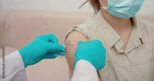 Adhesive bandage on arm after injection vaccine or medicine, Asian woman sitting in a clinic wearing a mask is injected with a vaccine to immunostimulating medication during a coronavirus outbreak. photo