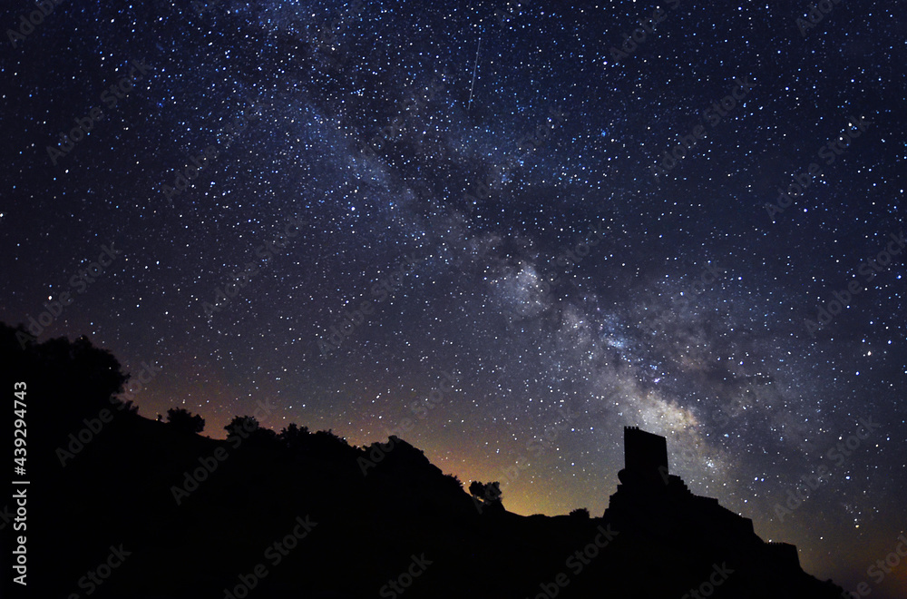 the milky way and the stars next to a castle