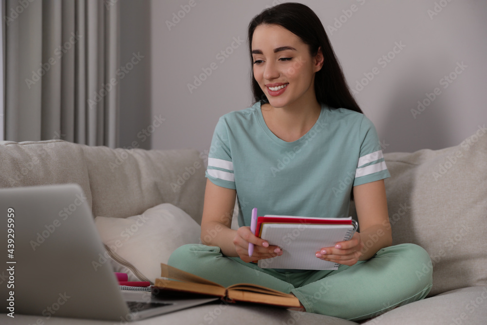 Young woman watching webinar on sofa at home Young woman watching webinar on sofa at home