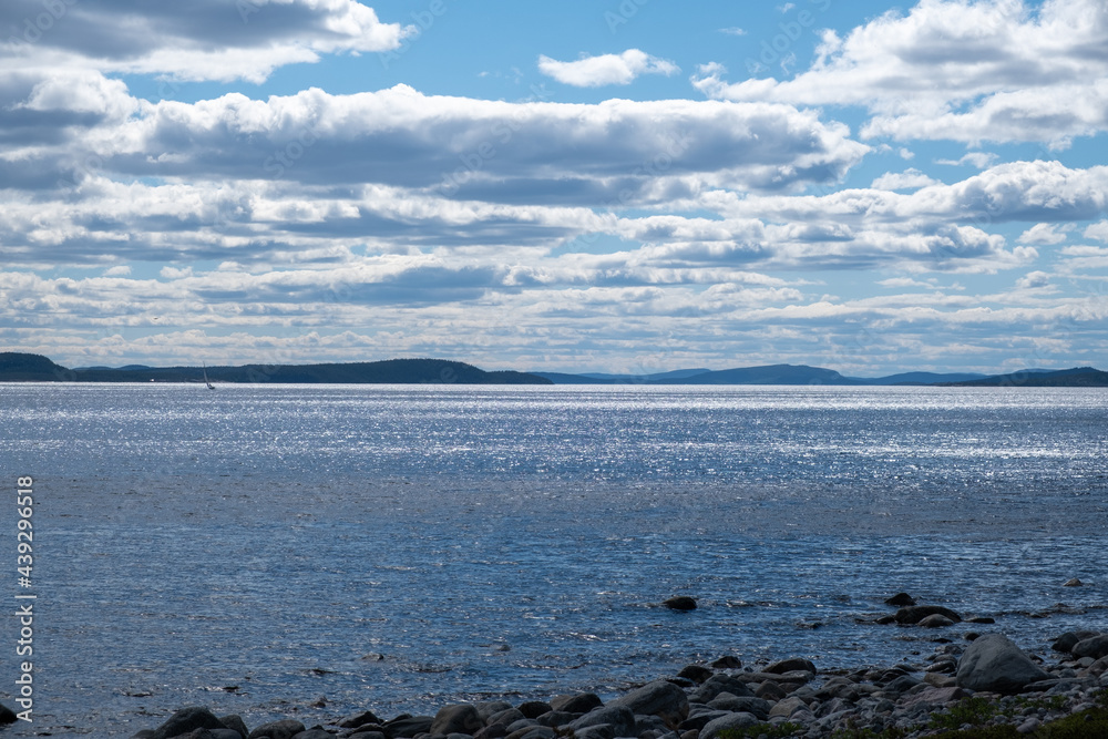 Many clouds with blue sky over the sea with mountains and rocks