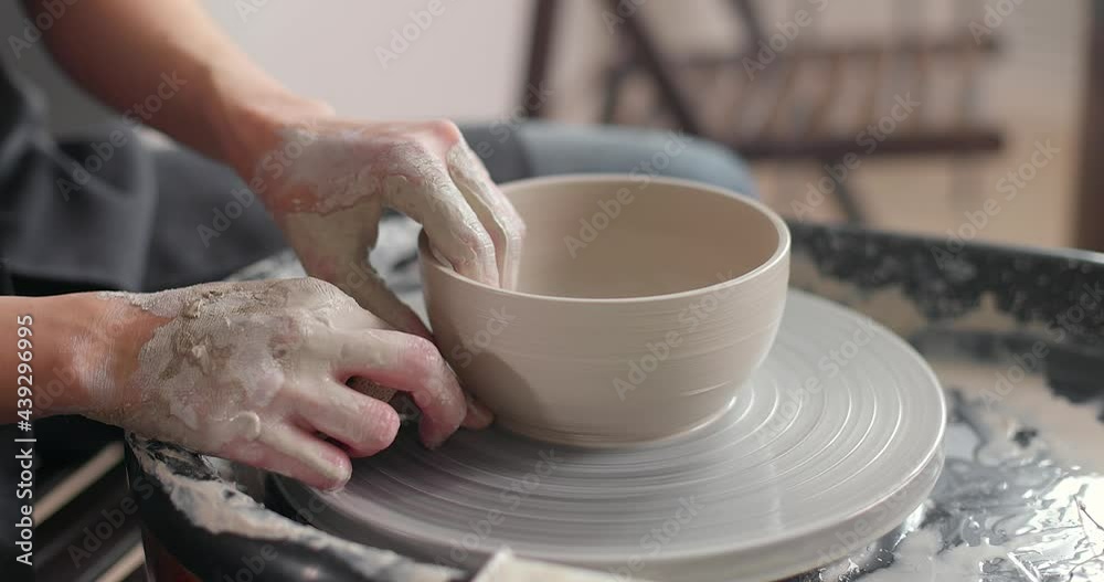 Handmade ceramics concept. Close-up of woman's hands in pottery studio. Cuts the workpiece from pottery wheel. Top view. Slow motion Handmade ceramics concept. Close-up of woman's hands in pottery studio. Cuts the workpiece from pottery wheel. Top view. Slow motion