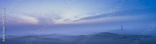 Fototapeta Naklejka Na Ścianę i Meble -  A lighthouse at dawn in the mist and fog under a purple sky