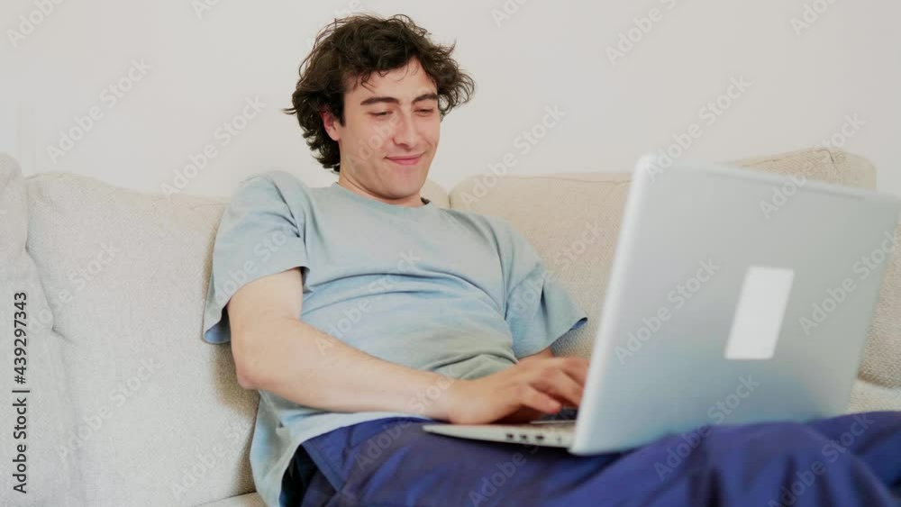 Young man sitting on couch having a video call on his laptop Young man sitting on couch having a video call on his laptop