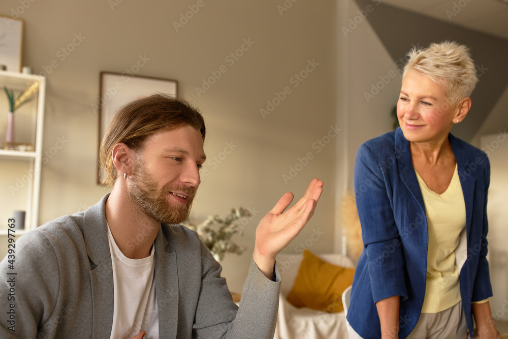 Fototapeta premium Team of two creative coworkers brainstorming at office. Stylish unshaven man gesturing emotionally sharing idea about startup business or new promising project, having meeting with female colleague
