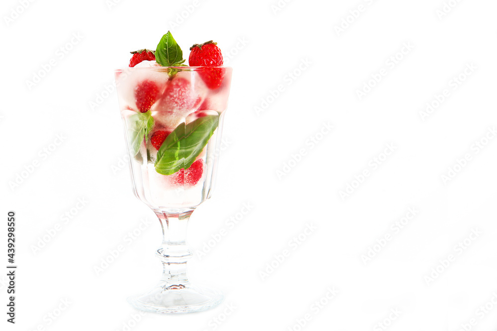 Fresh strawberries with chunks of ice in a glass . Basil leaves. Strawberry lemonade in a transparent glass. Copy of space. White background.Refreshing drink. Fresh strawberries with chunks of ice in a glass . Basil leaves. Strawberry lemonade in a transparent glass. Copy of space. White background.Refreshing drink.