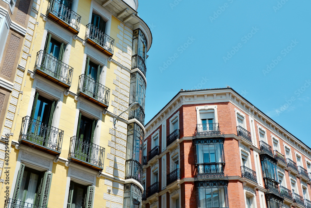 Classical yellow and red buildings with elegant metallic balconies in Chueca district downtown Madrid, Spain