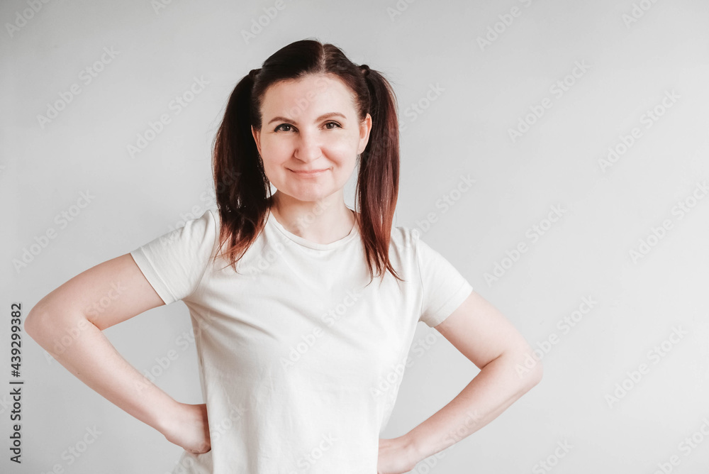 Beautiful woman with pigtails and a funny face wearing a T-shirt on a white background. Copy, empty space Beautiful woman with pigtails and a funny face wearing a T-shirt on a white background. Copy, empty space