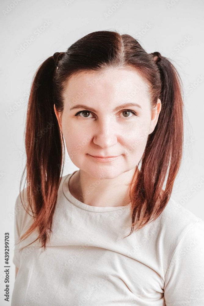 Beautiful woman with pigtails and a funny face wearing a T-shirt on a white background. Copy, empty space Beautiful woman with pigtails and a funny face wearing a T-shirt on a white background. Copy, empty space