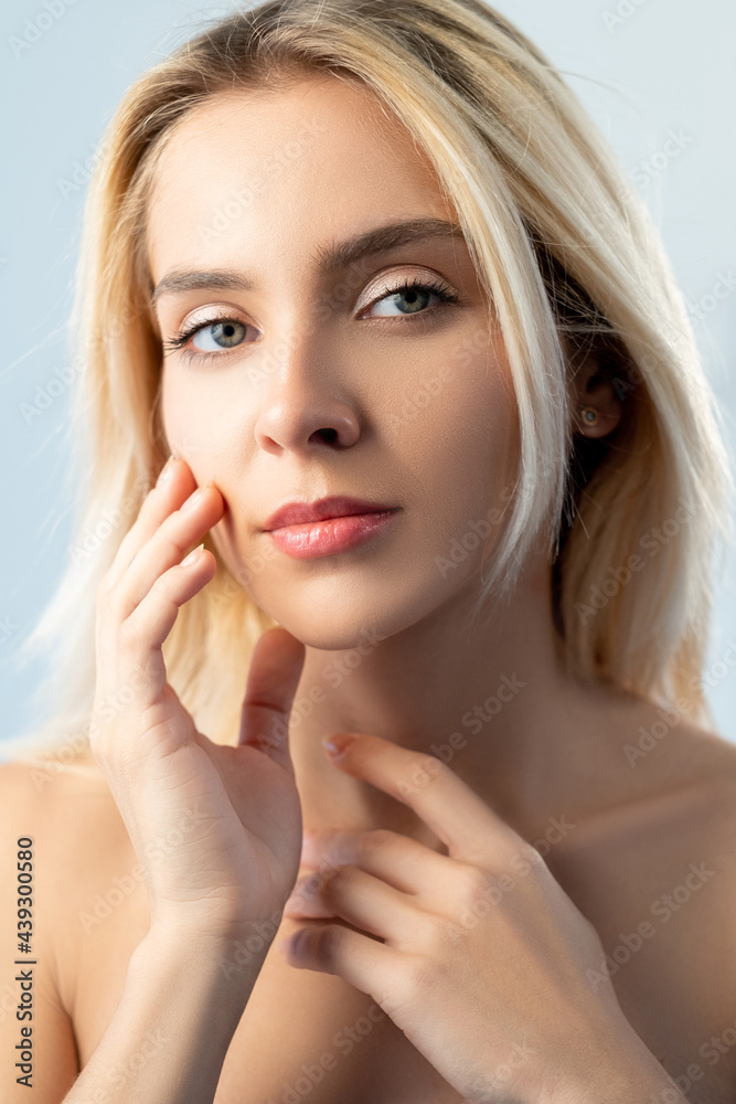 Anti-aging skincare. Skin rejuvenation. Aesthetic cosmetology. Relaxed woman with natural makeup touching flawless radiant face isolated on light. Anti-aging skincare. Skin rejuvenation. Aesthetic cosmetology. Relaxed woman with natural makeup touching flawless radiant face isolated on light.