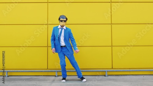 Cool businessman in monkey mask dancing in front of yellow wall