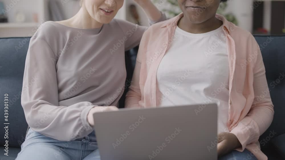 Caucasian and african female friends using laptop together, online shopping Caucasian and african female friends using laptop together, online shopping