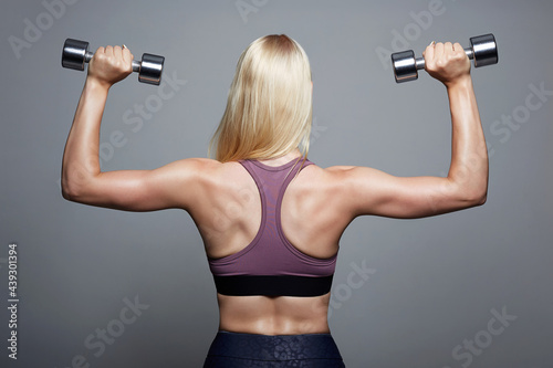 back of athletic girl. gym concept. muscular fitness woman with dumbbell