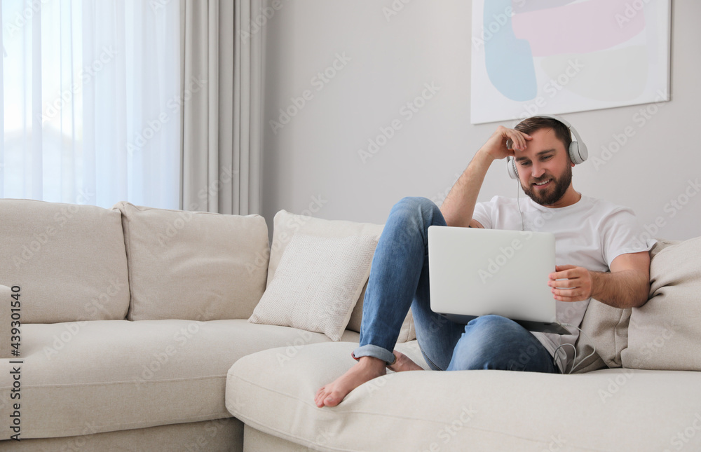 Man with laptop and headphones sitting on sofa at home Man with laptop and headphones sitting on sofa at home