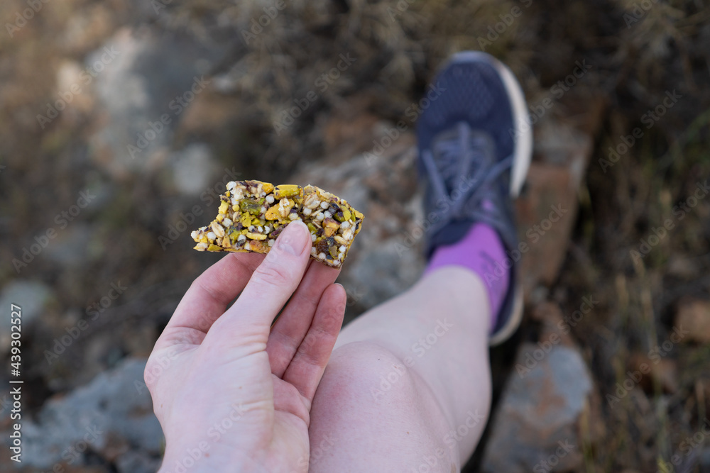 Sweet healthy and hearty food. Hand holding fitness bar. Healthy sweets for runners. Bar of nuts and honey for hiking Sweet healthy and hearty food. Hand holding fitness bar. Healthy sweets for runners. Bar of nuts and honey for hiking
