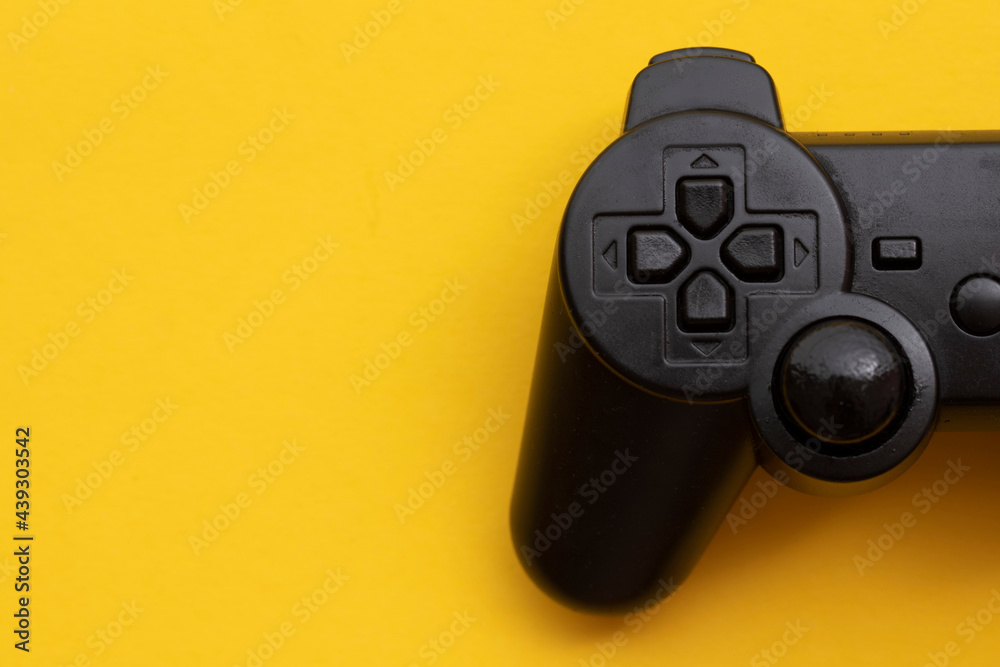 Black video game controller on a bright yellow background Black video game controller on a bright yellow background