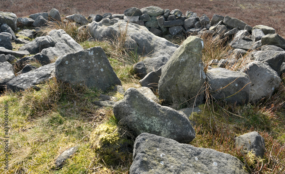 exposed stones at the top of a cairn known as the millers grave on midgley moor in calderdale west yorkshire with pennine moorland scenery