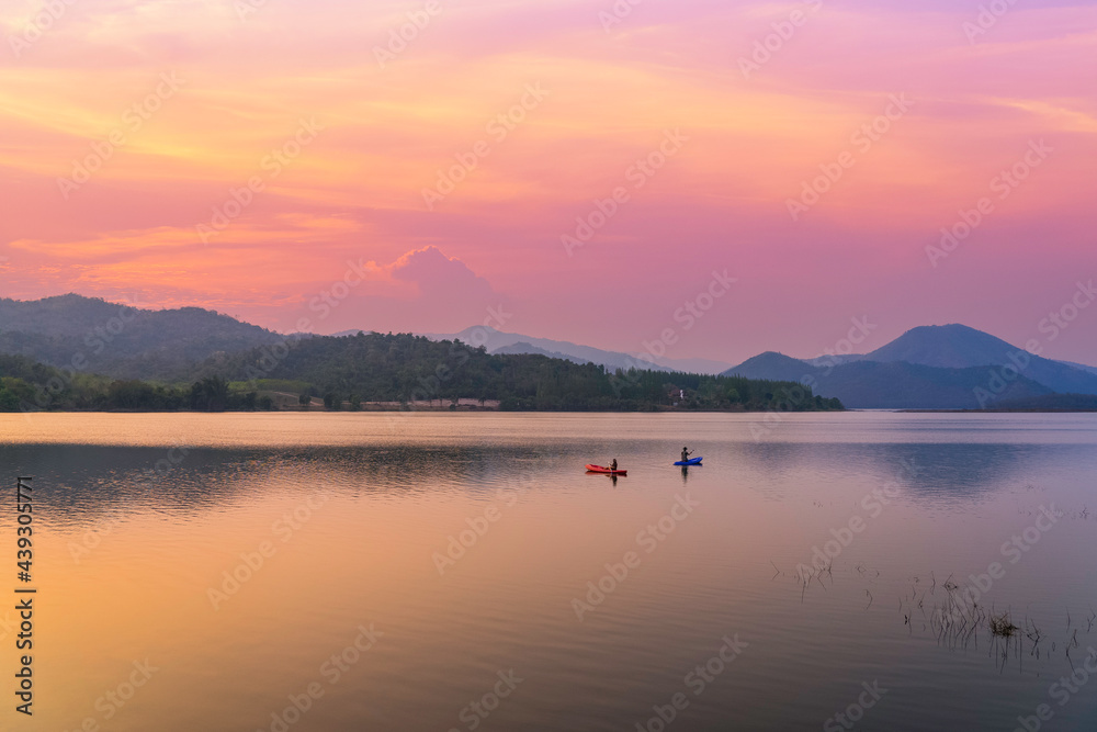 Couple kayaking together in the river with sunset sky and mountain background Couple kayaking together in the river with sunset sky and mountain background