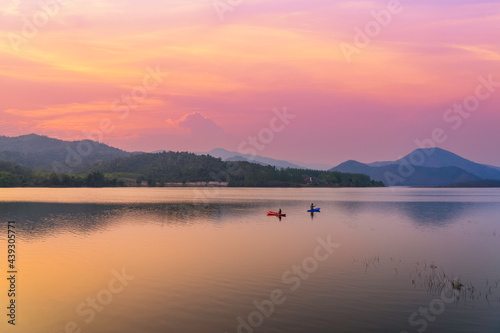 Couple kayaking together in the river with sunset sky and mountain background © mr_gateway