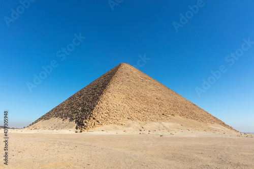 Old big pyramid with the blue cloudless sky on the background.