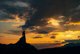 Silhouette of the bride standing on the rocks in the mountains at sunset 