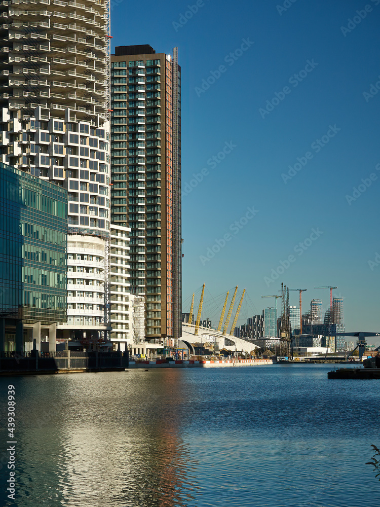 A collection of modern residential skyscrapers, part of the docklands regeneration, beside the Thames and ahead of the Millennium Dome.