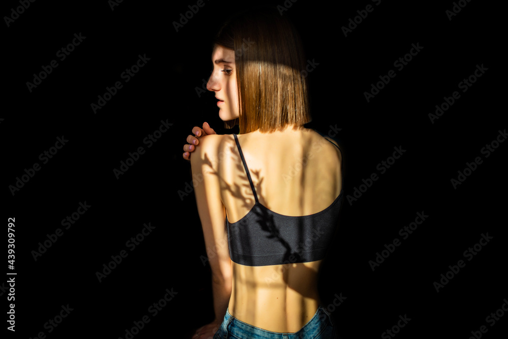 Obraz premium Beauty portrait of a back beautiful young girl with a shadow pattern on the face and body in the form of stripes. fashion, beauty. Female clavicle of green leaves. Close up.