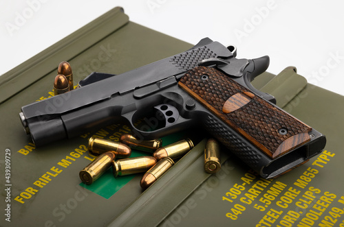 Automatic hand gun and ammunition on green bullet box background