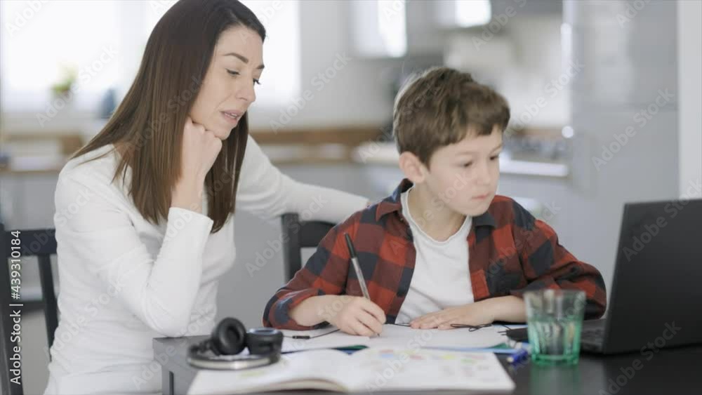 Mother helping son with homework on laptop Mother helping son with homework on laptop