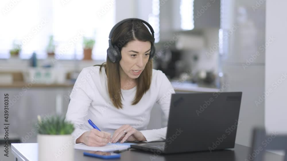 Woman taking notes while talking on video call Woman taking notes while talking on video call