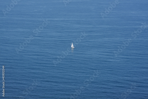 Lonely white sailing boat in the middle of a calm sea.